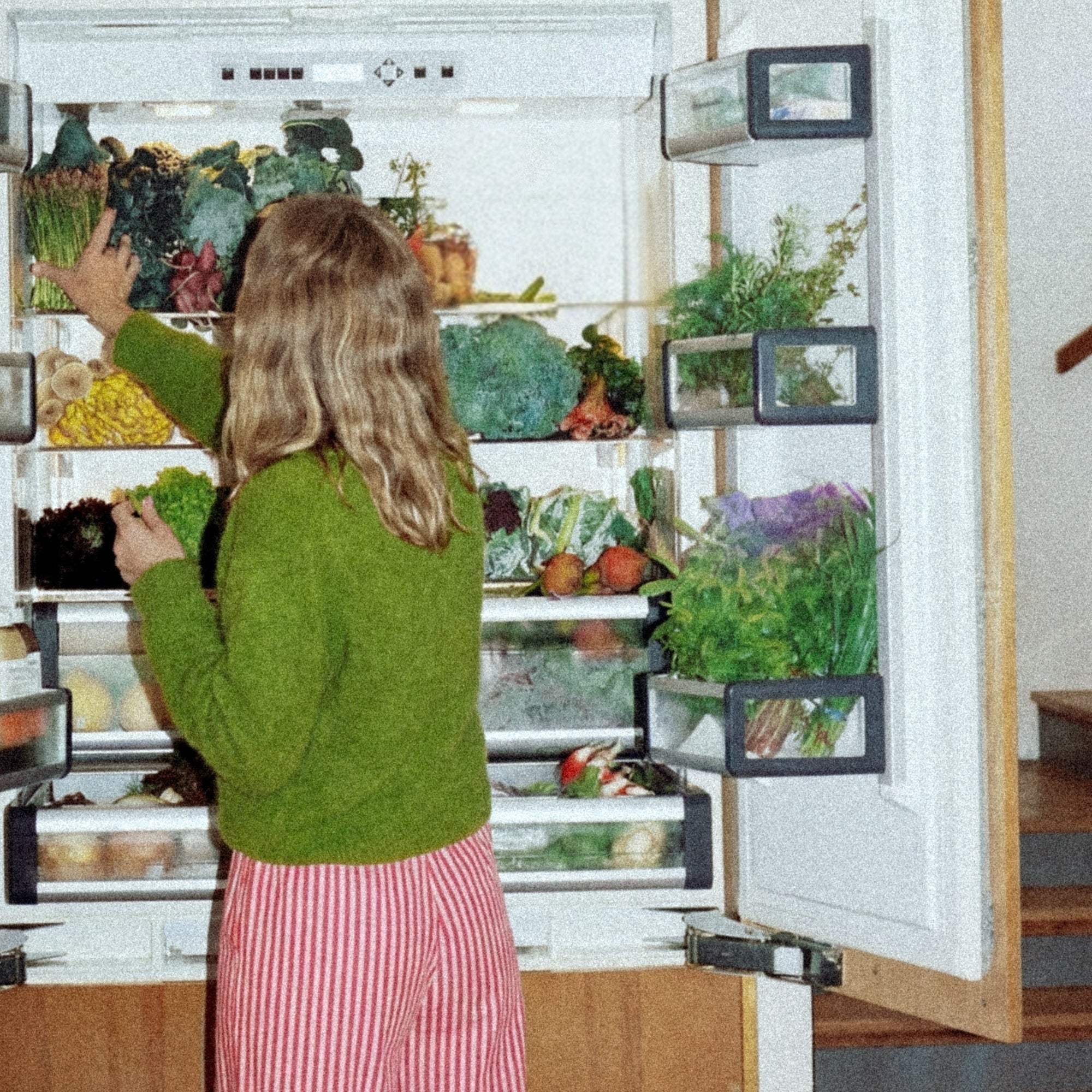 Woman picking vegetables from refrigerator 